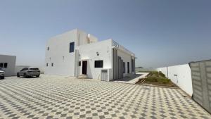 a white building with a car parked in front of it at Al REEF in Billah