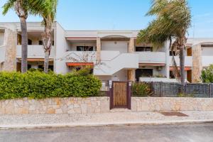 a building with a gate and palm trees at Stella Maris a Porto Cesareo in Porto Cesareo