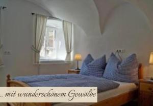 a bedroom with a bed with blue pillows and a window at Priestereck in Obernberg am Brenner