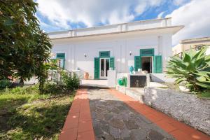 a white house with green shutters and a pathway at La Casa Bianca in Lipari