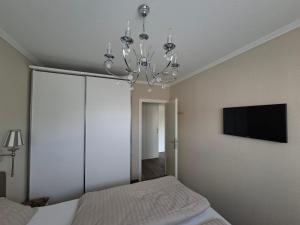 a bedroom with a bed and a chandelier at App 17 Haus Nordland in Sylt