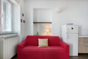 a red couch in a kitchen with a white refrigerator at Casa mare montaretto 2 in Bonassola