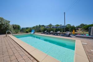 a swimming pool with chairs and umbrellas next to it at Podere Chinco - Gavorrano in Gavorrano