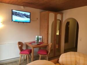 a room with a table and chairs and a tv on the wall at Gästehaus Hochstaffl in Gerlos