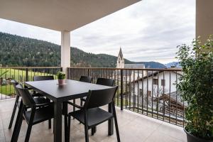 a balcony with a table and chairs and a church at Apartment Klara in Meltina