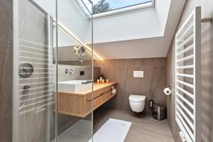 a bathroom with a sink and a toilet and a skylight at Chalet Bergfreund in Valdaora +24 photos