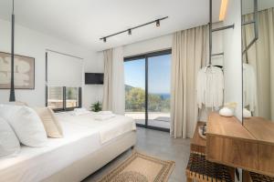 a white bedroom with a large bed and a large window at Nimbus Villas in Kalamitsi +33 photos