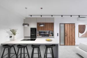 a kitchen with white counters and bar stools at Nimbus Villas in Kalamitsi