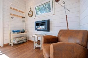 a living room with a chair and a tv at Casa Arbol in Camarles
