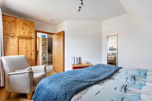 a bedroom with a bed and a chair at Bi uns to hus - Obendsünn in Nordstrand