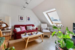 a living room with a red couch and a table at Bi uns to hus - Obendsünn in Nordstrand