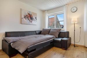 a leather couch in a living room with a clock on the wall at Bodenseenest in Meckenbeuren