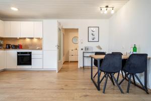 a kitchen with white cabinets and a table and chairs at Bodenseenest in Meckenbeuren