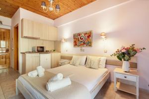 a bedroom with a white bed and a kitchen at Nontas Homes 36 in Kalamitsi