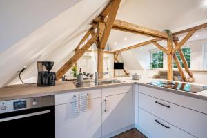 a kitchen with white cabinets and wooden beams at Schwalbenloft in Wagenfeld