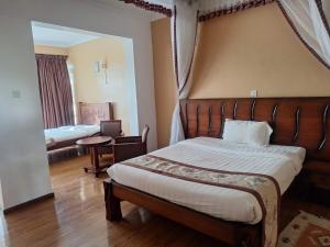 a bedroom with a large bed with a wooden headboard at Fairways Hotel in Narok +11 photos