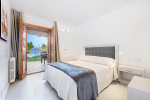 a white bedroom with a bed and a balcony at Ull de Bou in Port de Pollensa