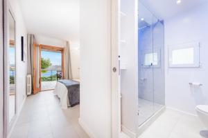 a white bathroom with a shower and a toilet at Ull de Bou in Port de Pollensa +9 photos