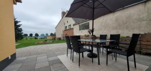 ein Tisch mit Stühlen und einem Sonnenschirm auf einer Terrasse in der Unterkunft Haus Oderbruch in Neulewin