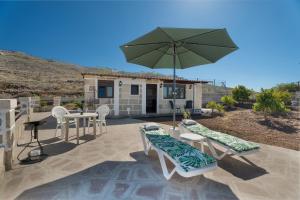 a patio with a table and chairs and an umbrella at Casa Eyden Sunset View in Arona