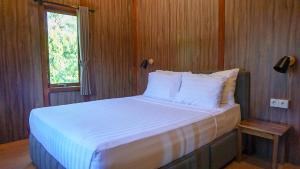 a bedroom with a bed with white sheets and a window at Rumah Gajah by Kubukubali in Pemuteran +32 photos