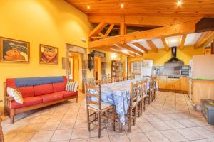 a dining room with a table and a red couch at Cal Viudet in Caserras