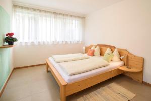 a bedroom with a wooden bed with a window at Peter Paul Gartenapt. Palme in Appiano Sulla Strada Del Vino