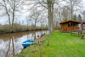 a cabin next to a river with a blue boat at Urlaub an der Elbmündung in Neuenkirchen