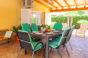 a dining room table with green chairs on a patio at Bona Mar in Cala Ratjada