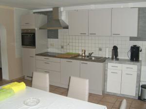 a kitchen with white cabinets and a table with chairs at Ferienwohnung Kelpin in Möllenbeck