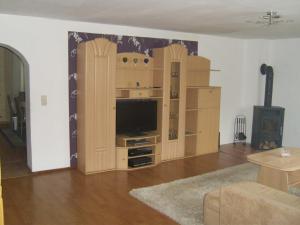 a living room with a tv and wooden book shelves at Ferienwohnung Kelpin in Möllenbeck