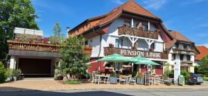 a building with tables and umbrellas in front of it at Pension Linde in Höchenschwand