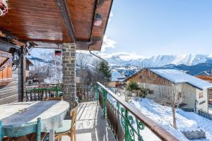a balcony with a table and chairs and snow covered mountains at Chalet les aiguilles in Albiez-Montrond