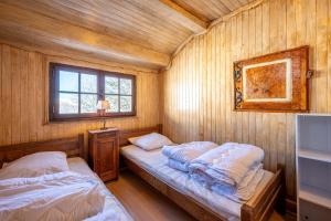 two twin beds in a room with wooden walls at Chalet les aiguilles in Albiez-Montrond