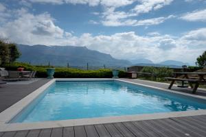 a swimming pool with a table and mountains in the background at Le Balcon des Bauges in La Motte-Servolex