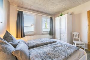 a bedroom with a large bed and two windows at Ferienhaus von Osten in Burg