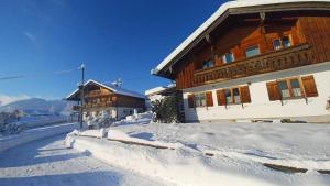 a building with snow on the side of it at Ferienwohnung Geierstein in Wackersberg