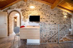 a room with a desk and a tv in a stone wall at Appartamento Gufo in Tremosine Sul Garda