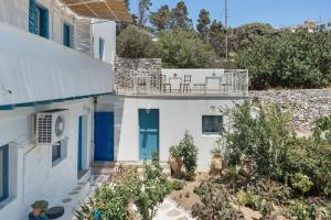 a white house with a blue door and plants at Politimi Studio N8 in Amorgos