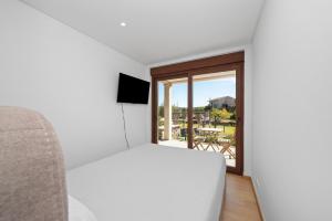 a bedroom with a white bed and a window at Terra Nossa com Piscina aquecida in Vila Real