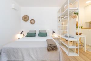 a white bedroom with a white bed and shelves at Bacom Apartment in Caldes de Malavella