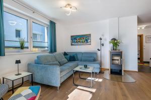 a living room with a blue couch and some windows at Ferienwohnung Edelstein in Neukirchen am Großvenediger