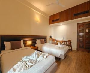 a hotel room with two beds and a table at Hotel Tragopan in Dimāpur +72 photos