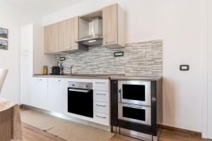 a kitchen with white cabinets and a stove at Villa Vacanze Pink Lady in Tuenno