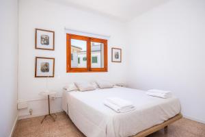 a white bedroom with a bed and a window at Can Manuel in Felanitx