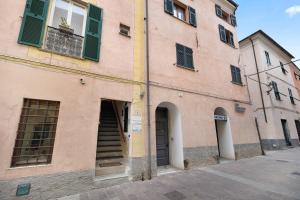 a pink building with green shutters on a street at Ultimo Tiro - app Secondo Tiro in Cisano sul Neva