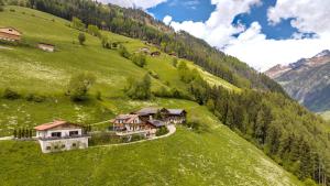 an aerial view of a house on a green hill at Tratterhof Apt Astjoch in Vandoies +25 photos