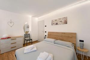 a white bedroom with a bed and a chair at Appartamento Bucaneve - Padola in Padola
