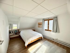 a white bedroom with a bed and a window at Backhüsli am Bauerngarten in St. Blasien