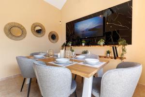 a dining room with a table and chairs and a tv at Te Mahana Nei House in Costa Calma